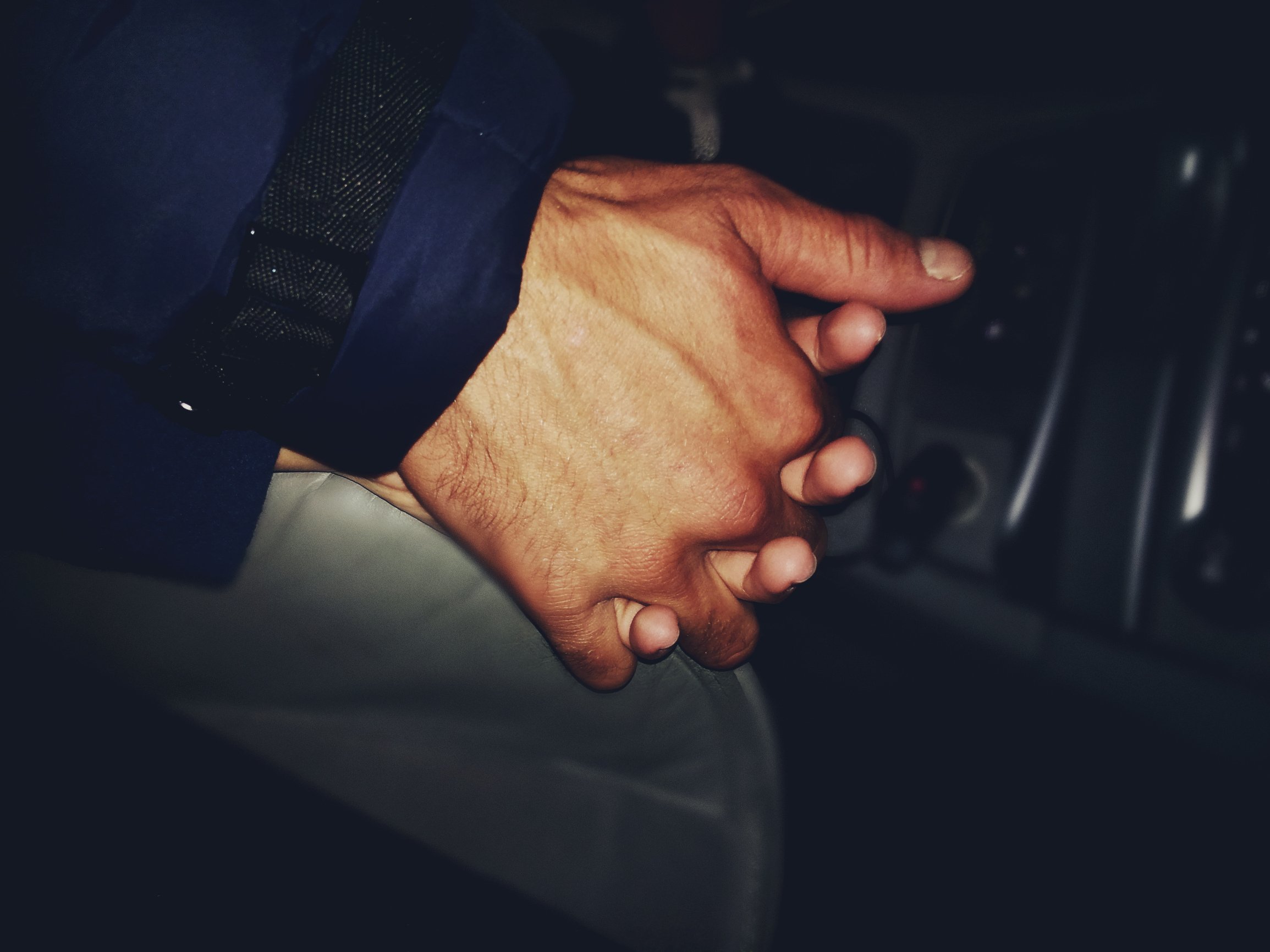 Фото двух рук в машине в темноте