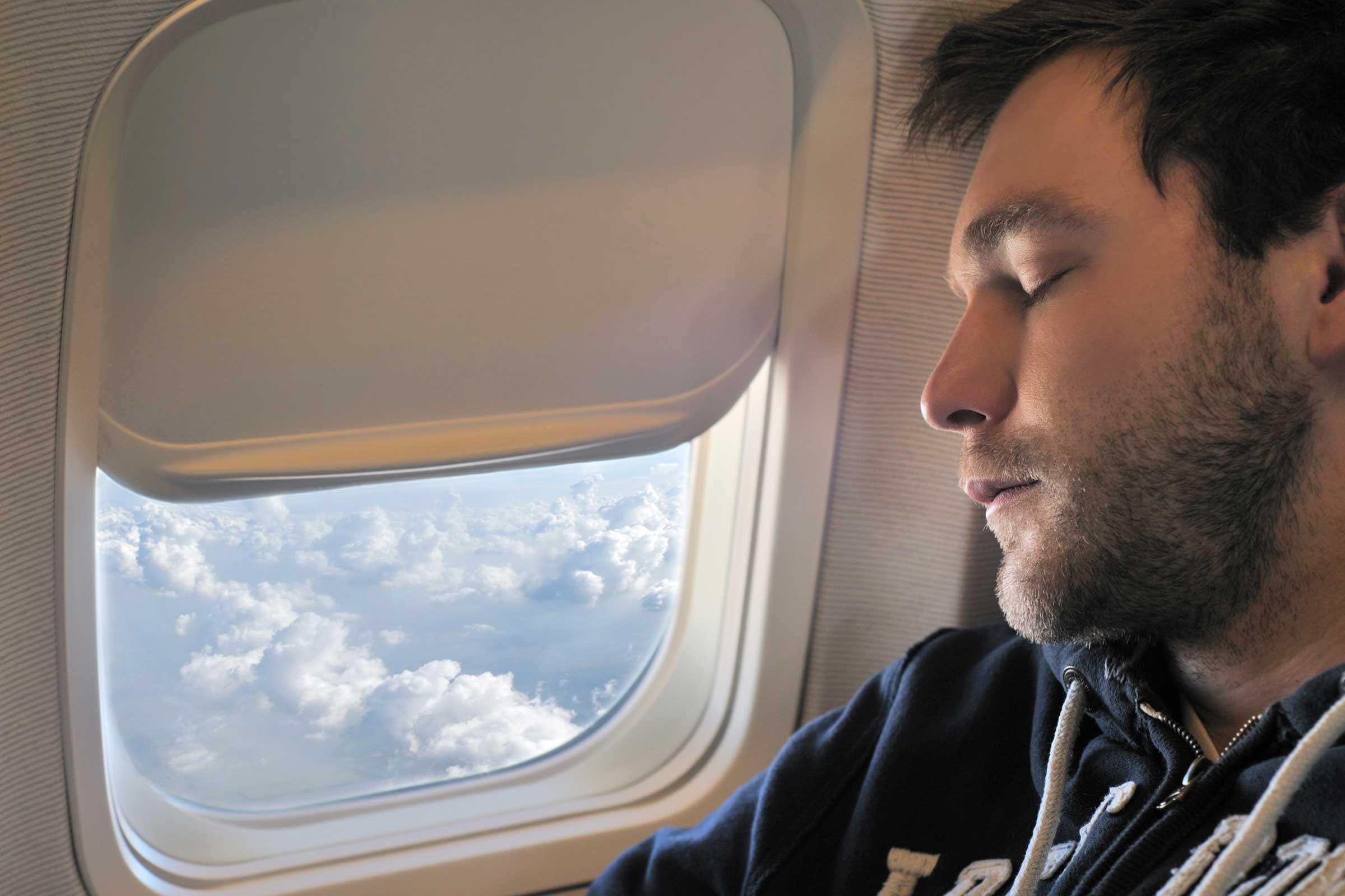 Ночью пассажиры утомленные долгим путешествием дремали. Мужчина в самолете. Парень в самолете. Самолет с пассажиром. Люди в самолете.