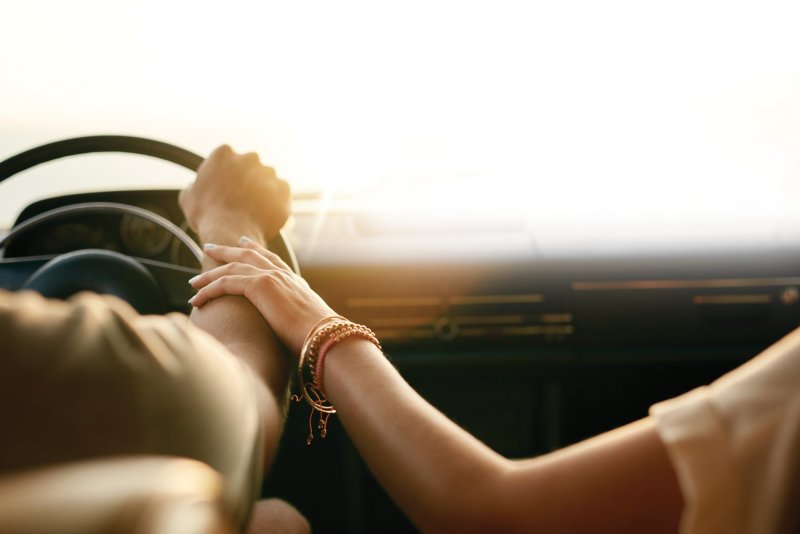 Пара едет в машине и держаться за руки